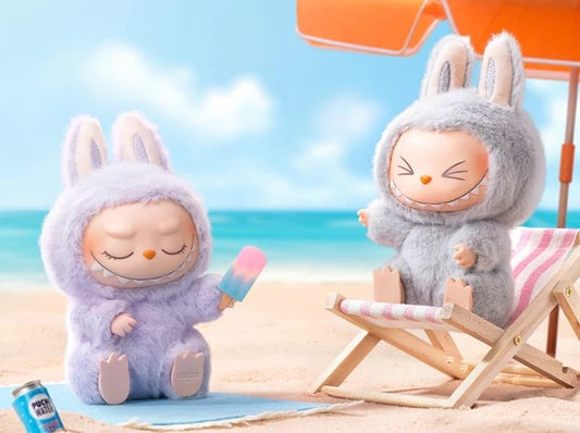 Two plush toys in bunny costumes on a beach with a blue sky and ocean.
